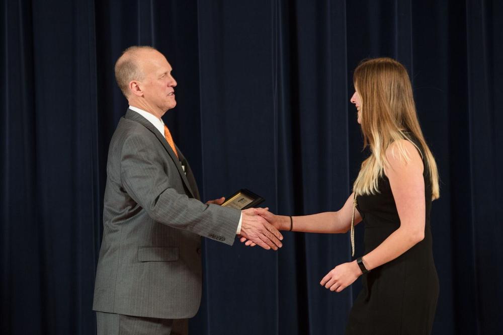 Doctor Potteiger shaking hands with an award receipient in a black dress